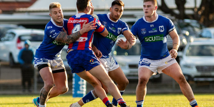 Newtown Jets players (from left) Aaron Gray, Briton Nikora and Daniel Vasquez have this Newcastle Knights player bailed up in a match at Henson Park in 2018. Photo: Mario Facchini, mafphotography.